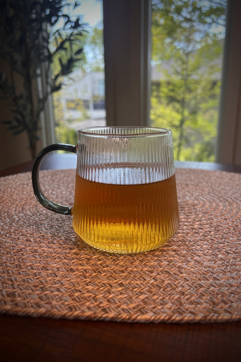 glass cup containing midnight blend tea infusion. pale gold with a hint of green color.