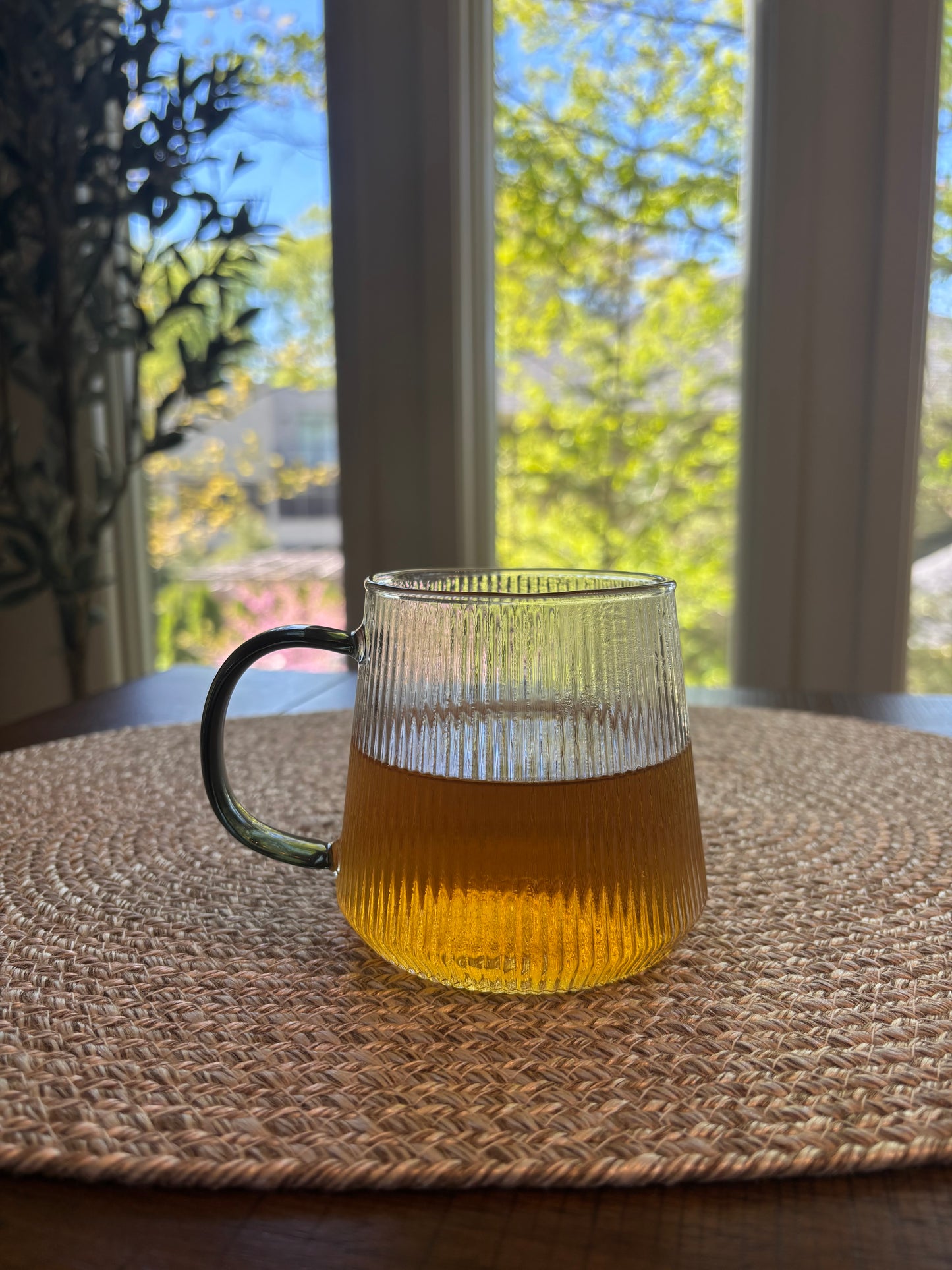 glass cup containing the tea which is a soft amber