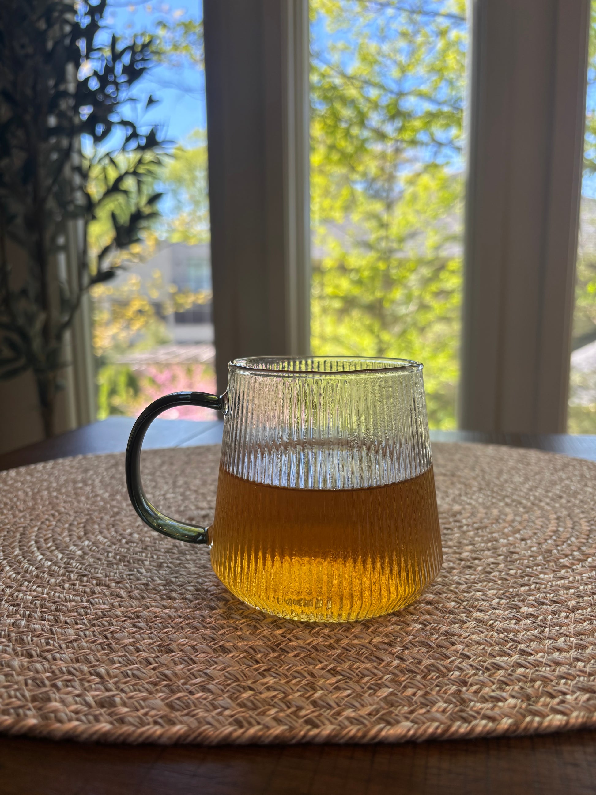 glass cup containing the tea which is a soft amber